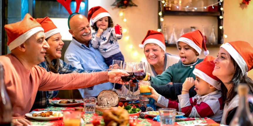 Familie am großen Tisch stößt mit Wein auf das Essen an